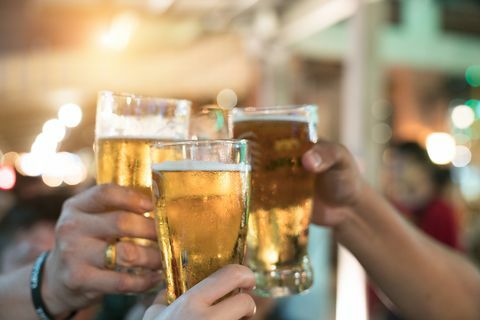 Freunde, die mit Gläsern hellem Bier an der Kneipe rösten. Schöner Hintergrund des Oktoberfestes. Eine Gruppe junger Leute beim Entspannen an der Bar. feinkörnig. Weicher Fokus. Flacher DOF.