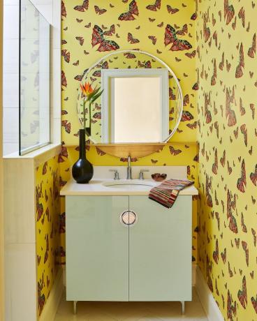 Damentoilette mit minzfarbenem Waschbeckenschrank und Schmetterlingstapete