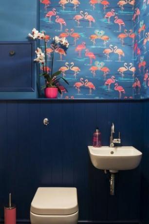 Badezimmer mit Flamingotapete, weißem Waschbecken und blauen Wänden.