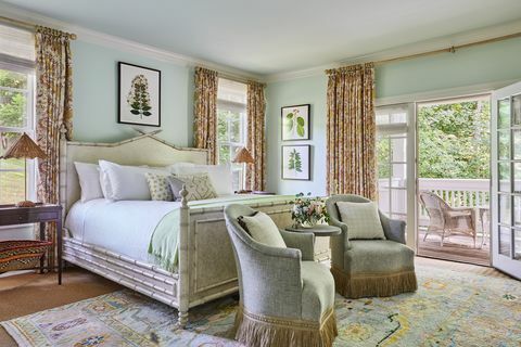 hellblaue Wände mit einem Bett mit einem cremefarbenen Kopfteil, weißen Laken und einer hellgrünen Decke