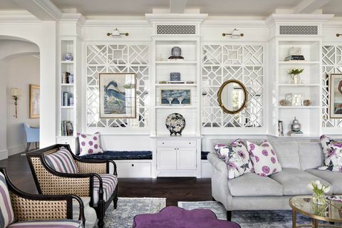 Wohnzimmer, graues Sofa, lila und weiße Dekokissen, weiße Aufbewahrungsschränke, lila Ottomane