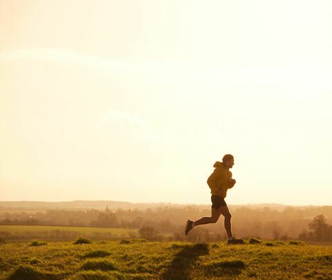 Jogger läuft auf Hügel bei Sonnenuntergang