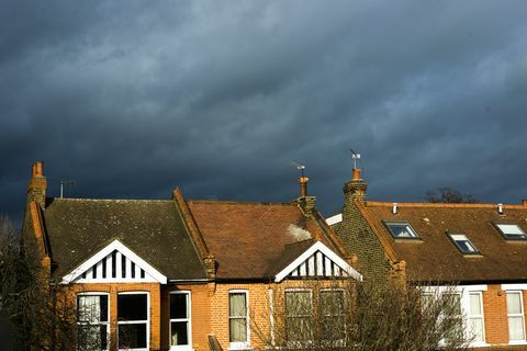 Drohende Wolken über sonnenbeschienenen Häusern