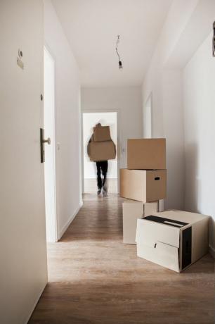 Bemannen Sie das Entladen von Pappschachteln in der Halle eines neuen Hauses