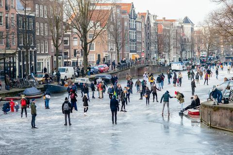 Dutzende von Menschen laufen auf den Amsterdamer Grachten