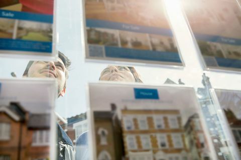 Paare, die Anzeige von Anzeigen im Immobilienmaklerfenster betrachten