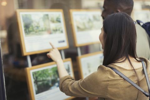 Junge Paare, die Immobilienlisten an der Schaufenster grasen