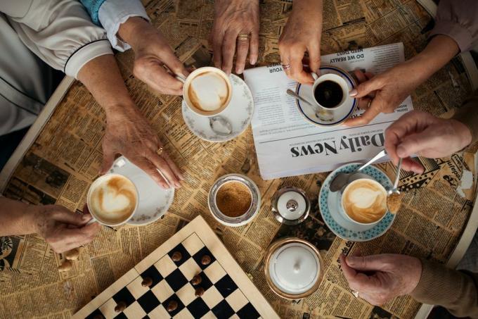 Ältere Freunde genießen die gemeinsame Zeit drinnen im Café direkt über der Aussicht