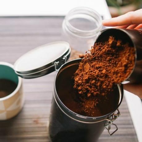 Kaffeesatz Garten abgeschnittene Hände gießen gemahlenen Kaffee in wiederverwendbaren Behälter