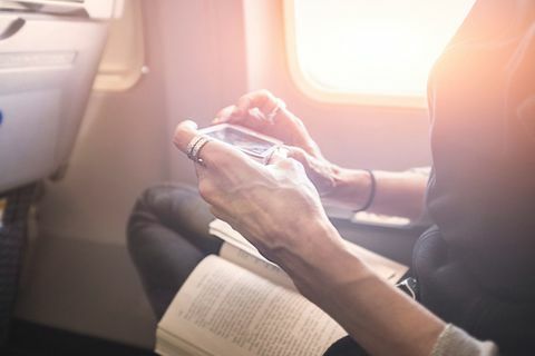 Person, die an Bord des Flugzeuges Spiel auf Smartphone spielt