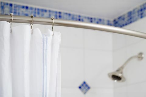Detail Duschvorhang und Duschkopf in blau und weiß gefliesten Dusche