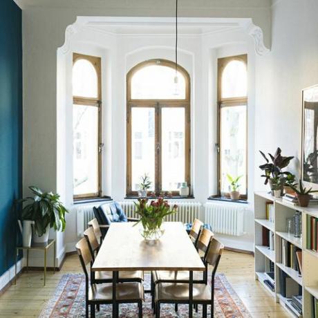 Holztisch und Stühle im modernen Wohnzimmer mit großer Fensterfront in stilvoller Wohnung