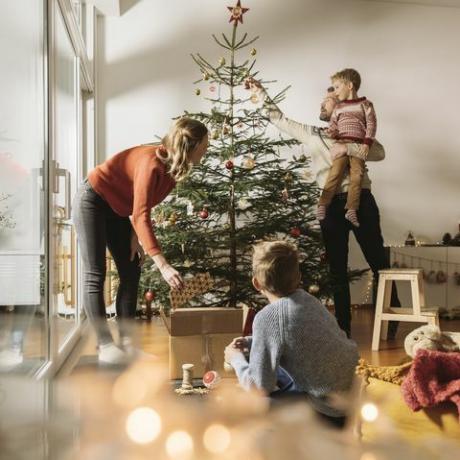 vierköpfige Familie schmückt ihren Weihnachtsbaum