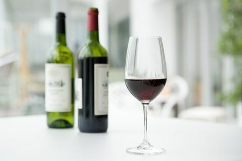 Rotwein in Flaschen und Glas auf weißer Tabelle