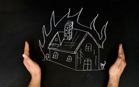 Hausversicherungs-Konzept-Mann, der Haus durch Hände vor Feuer schützt