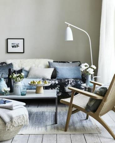 neutrales Wohnzimmer, Wohnzimmer mit Kissen auf dem blau gemusterten Sofa, eine gebogene weiße Stehlampe über dem Sofateam Tropfen, Flecken und Spritzermuster für einen impressionistischen Look, der zeitgenössisch ist und entspannt