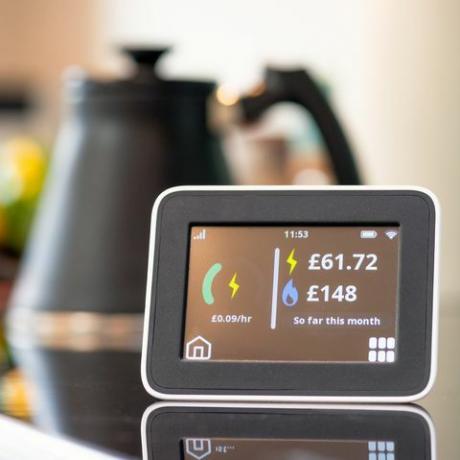 Nahaufnahme des Bildschirms eines Smart-Meter-Displays in einer Küche, das die bisherigen monatlichen Kosten für Strom und Gas anzeigt