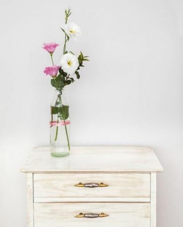 Aufbereitetes forniture mit Lisianthusblumenblumenstrauß gegen weiße Wand