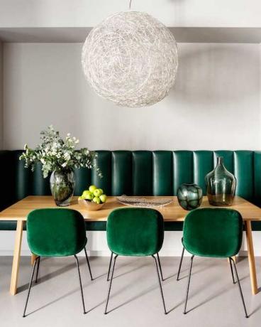 Esszimmer mit smaragdgrünen Stühlen und einem Statement-Licht