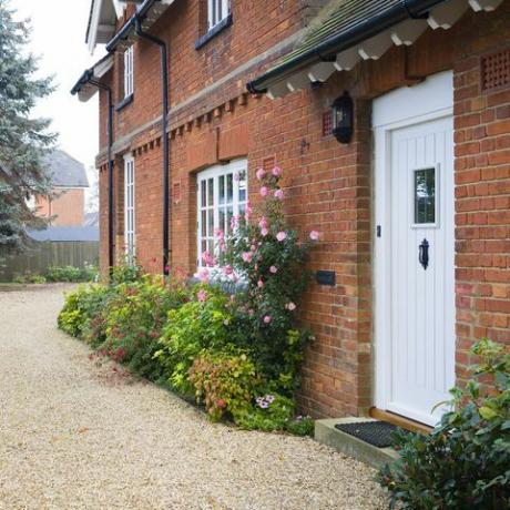 englisches Landhaus und Garten im Herbst mit Kiesauffahrt das Haus ist viktorianisch, mit Blumenrabatten gefüllt mit Sträuchern und Stauden