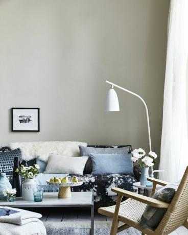 neutrales Wohnzimmer, Wohnzimmer mit Kissen auf dem blau gemusterten Sofa, eine gebogene weiße Stehlampe über dem Sofateam Tropfen, Flecken und Spritzermuster für einen impressionistischen Look, der zeitgenössisch ist und entspannt