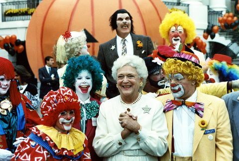 Dieses Foto zeigt die grinsende First Lady Barbara Bush, die mit kostümierten Darstellern, einer Gruppe, posiert von Clowns und ein einsamer Werwolf auf dem südlichen Gelände des Weißen Hauses als Teil eines Halloween Feier