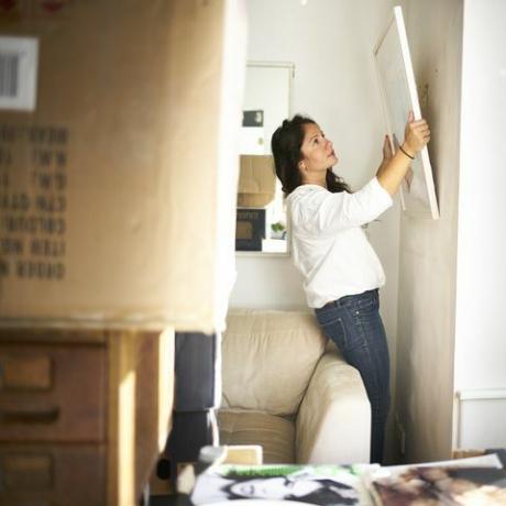 Frau, die ein Bild von der Wand macht, die bereit ist, während des Umzugs zu packen